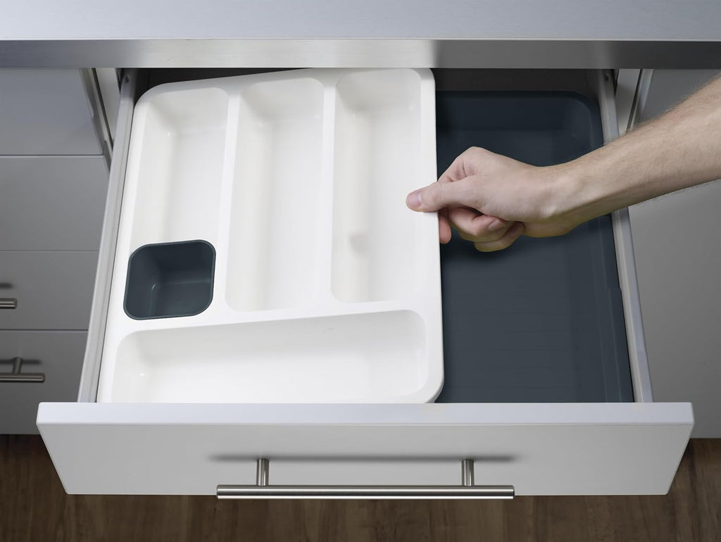 Expandable dark-gray six-compartment plastic cutlery drawer tray — tray installed in a drawer